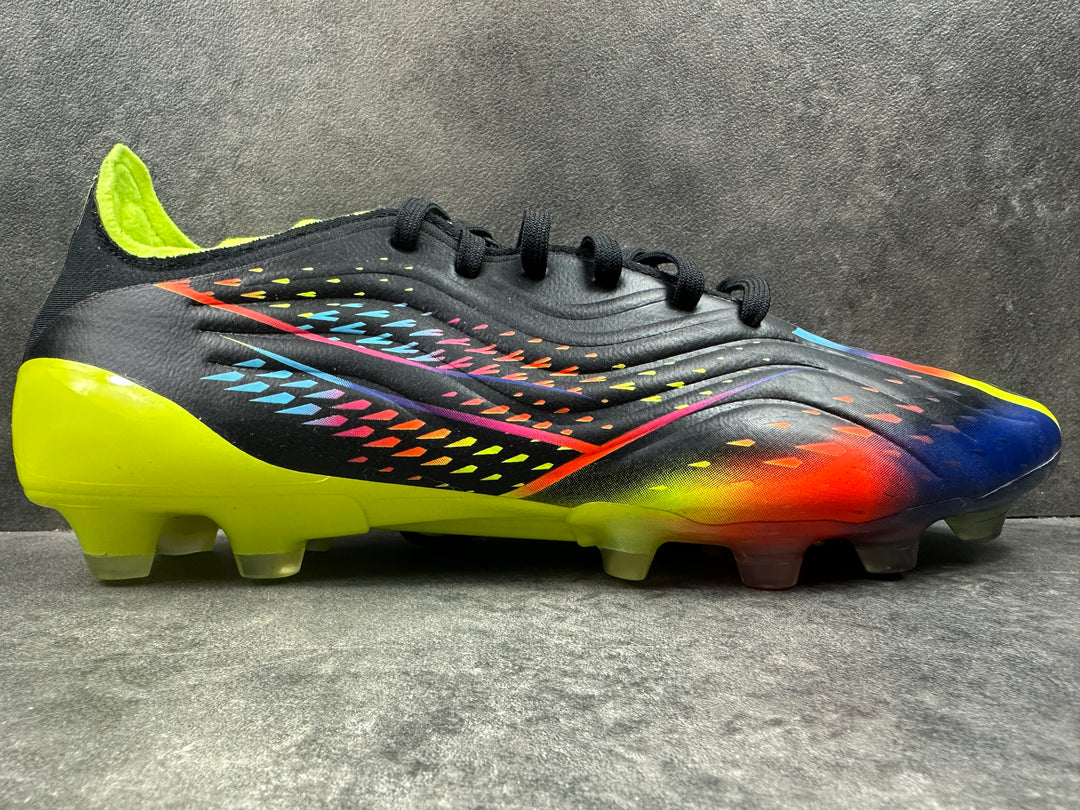 A pair of Adidas Copa Sense .1 HG soccer boots with a multicolored upper design, featuring black, yellow, and blue, with a soleplate visible in the image.