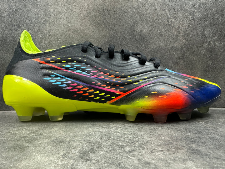 A pair of Adidas Copa Sense .1 HG soccer boots with a multicolored upper design, featuring black, yellow, and blue, with a soleplate visible in the image.