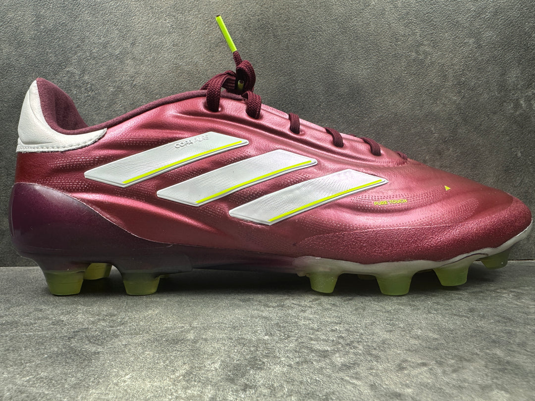 A single Adidas Copa Pure II HG soccer cleat in red with white accents and yellow laces, displayed against a textured background.