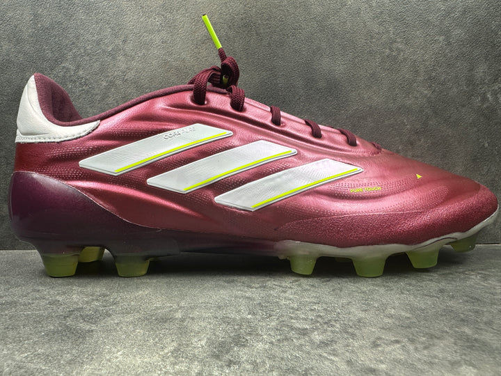 A single Adidas Copa Pure II HG soccer cleat in red with white accents and yellow laces, displayed against a textured background.